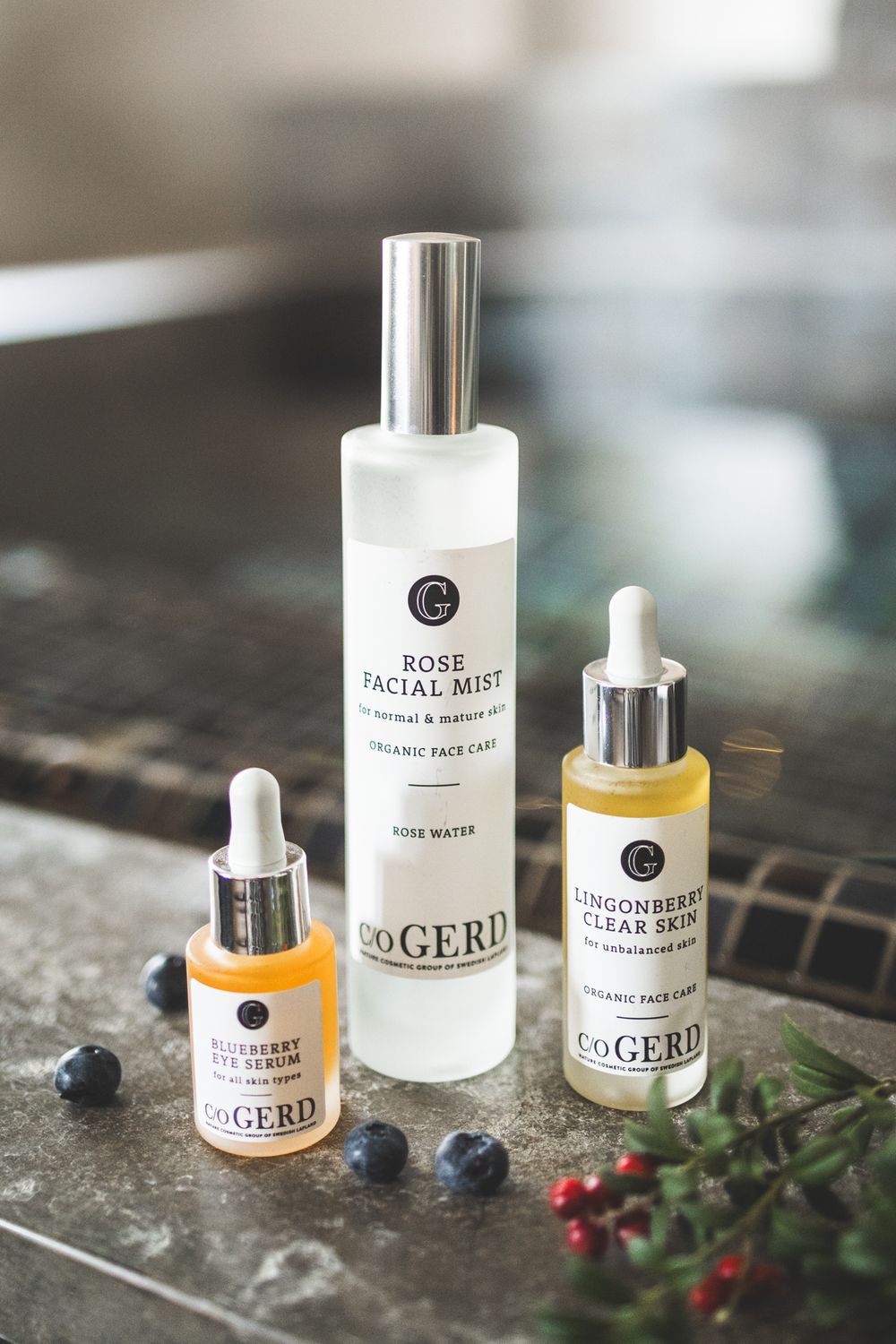A collection of skincare products including facial mist and serums arranged with natural elements on a textured surface.
