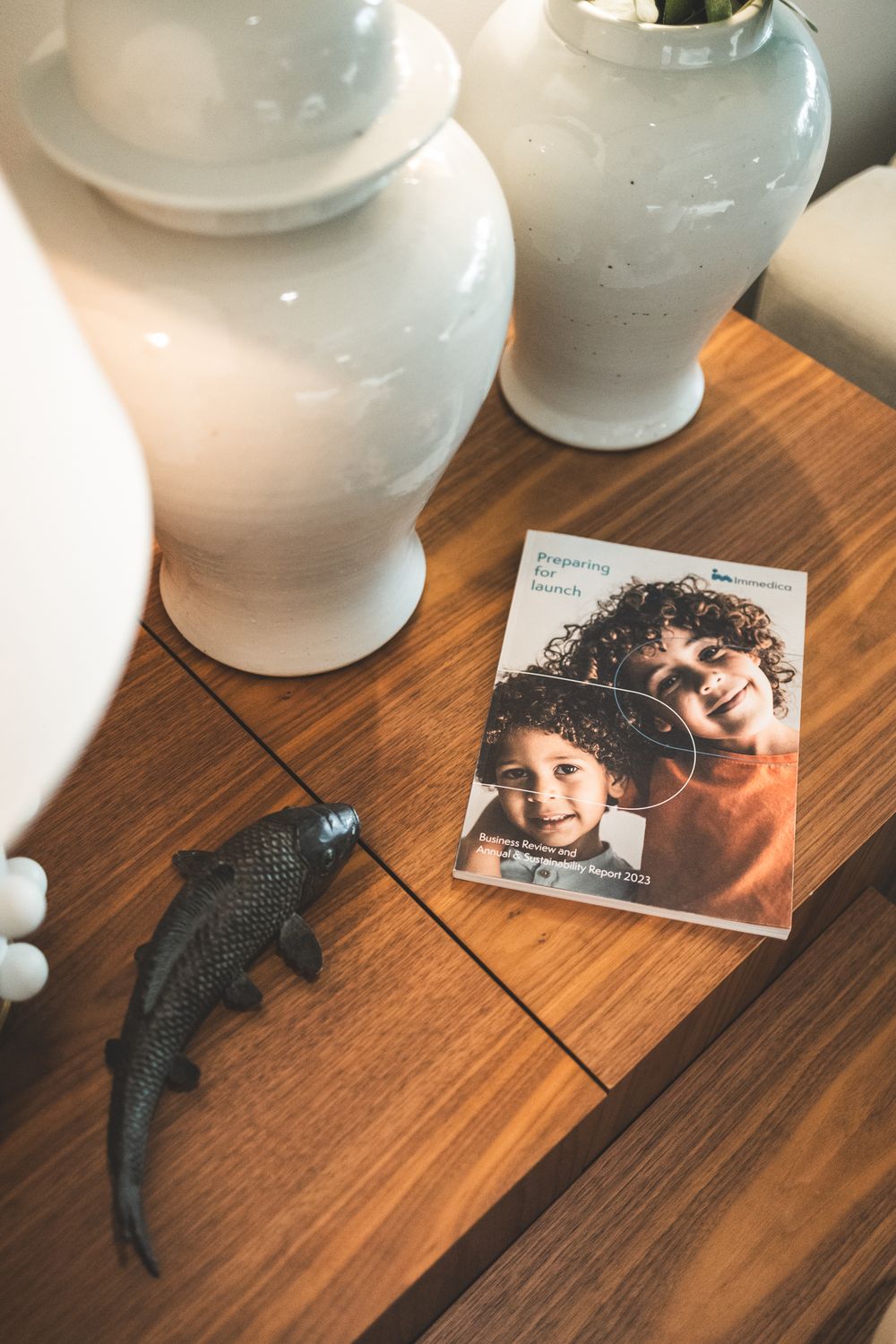 A black cat lying on a wooden table next to a photograph on a warm brown surface.