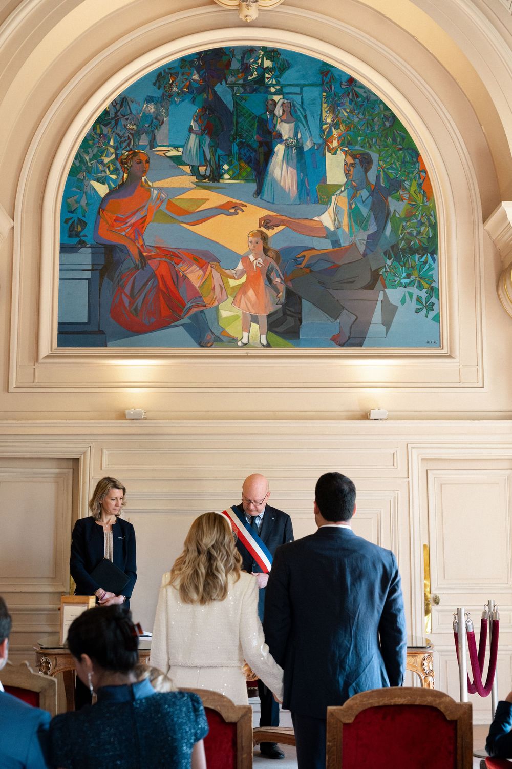 Colorful art murals adorn the arched walls above while people gather in an elegant room for a formal event. Paris elopement.