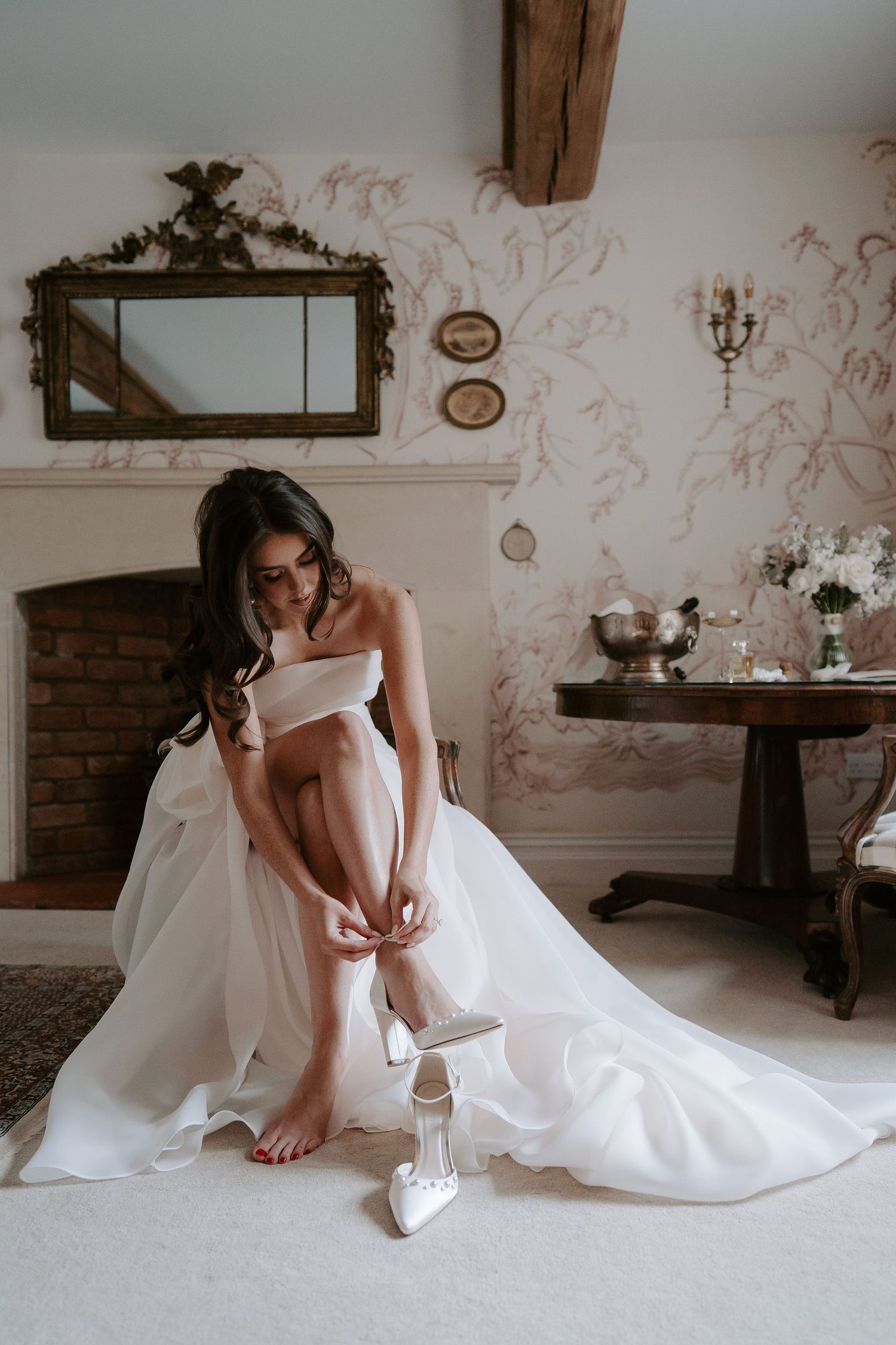 bride sat, fastening her shoes at dewsall court in herefordshire