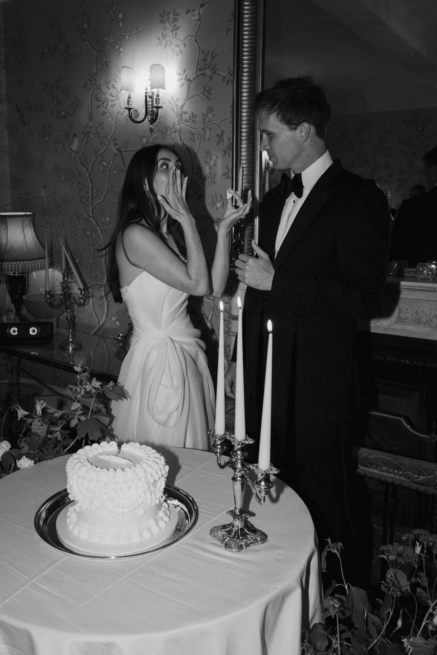 bride licking icing sugar off hand during the cake cut at dewsall court in herefordshire