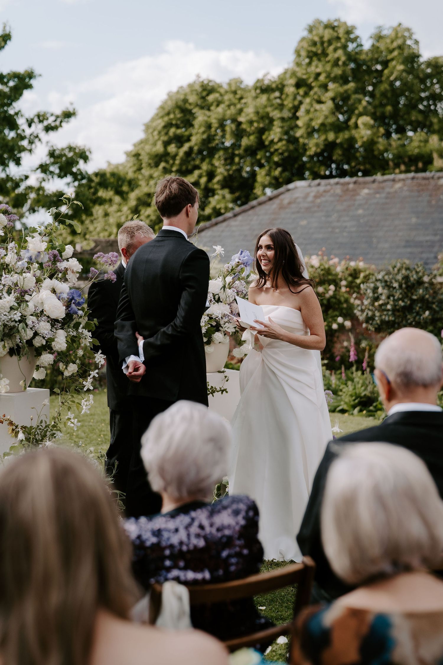 bride smiling at groom while reading vows during wedding ceremony at dewsall court in herefordshire