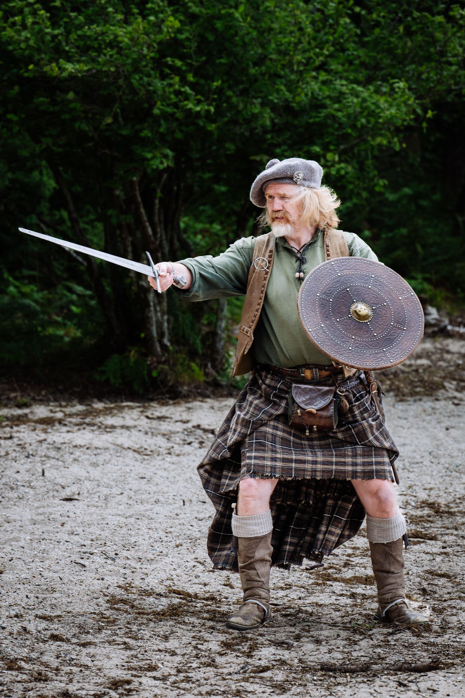 Scottish highland warriors demonstrating combat techniques with swords and shields.