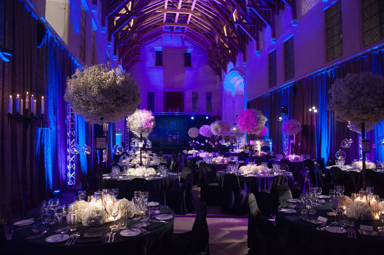 Elegant banquet hall decorated with dramatic purple uplighting and table settings.
