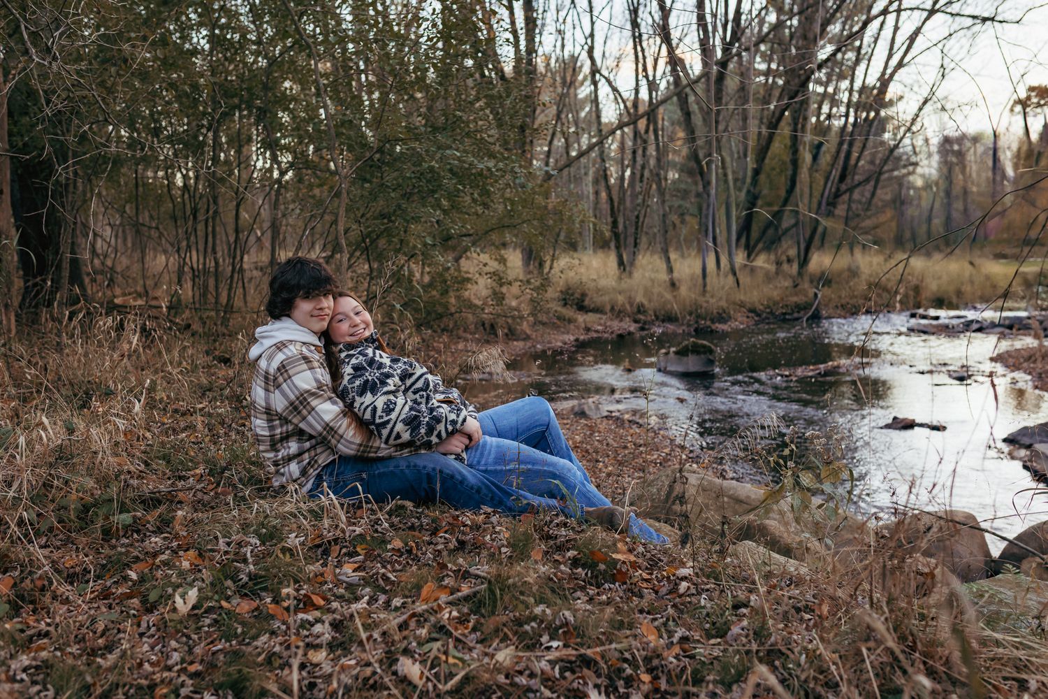 Couple cuddling by a river in Weston, Wisconsin during their relaxed couples photography session