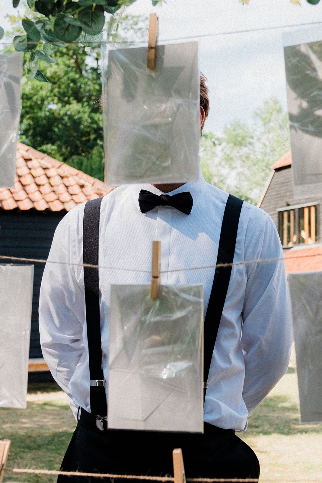 White dress shirts hanging on a clothesline outdoors with wooden clothespins against a garden background.