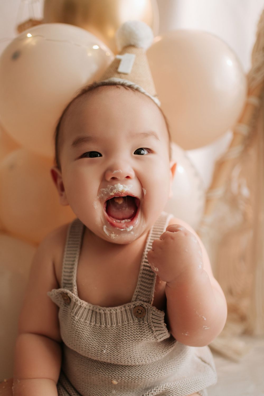 A series of five close-up photos showing a baby in beige overalls expressing joy and laughter.