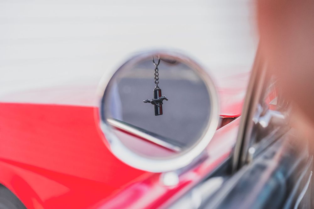 Close-up detail shot of chrome trim and emblems on a classic red Mustang.