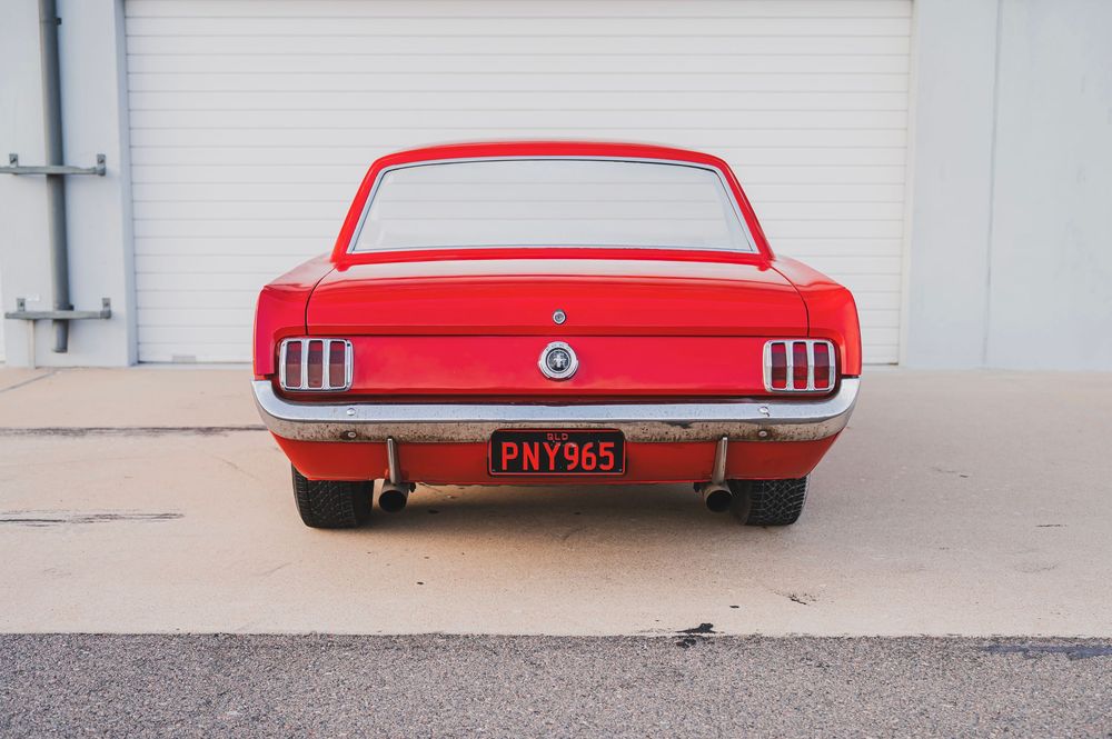 Rear view of a red classic Mustang highlighting its distinctive taillights and rear design.
