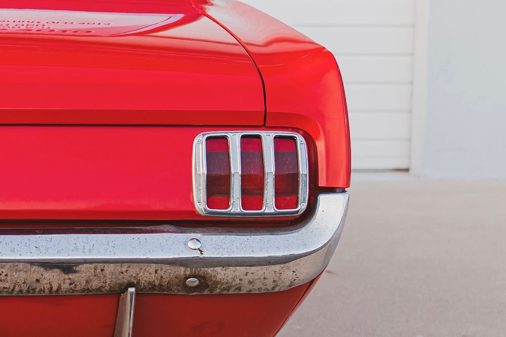 Close-up views of a classic red Ford Mustang's exterior details including taillights and body panels.