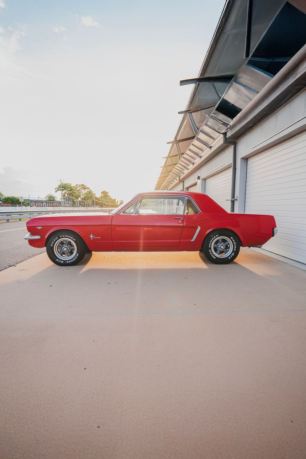 A series of six photos showing a red classic Ford Mustang parked at different angles outside a white garage.