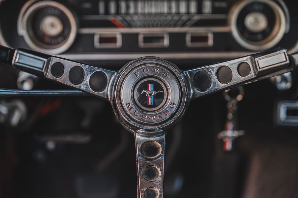 Vintage Ford Mustang steering wheel and dashboard details shown in dramatic black and white photography.
