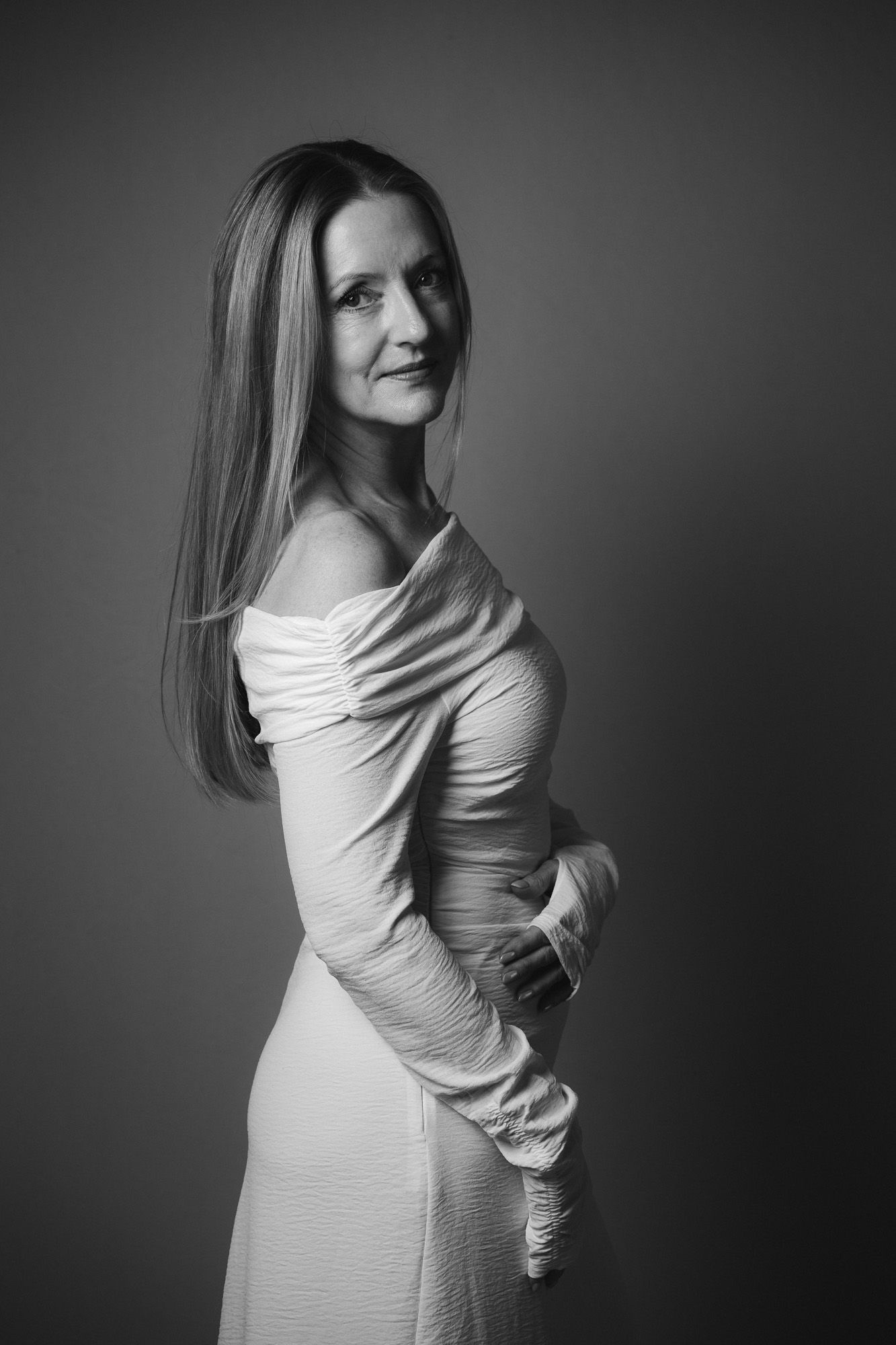 full-length portrait of a woman with long hair in a white off-shoulder dress taken in a studio in King's Lynn by N-lite Photography