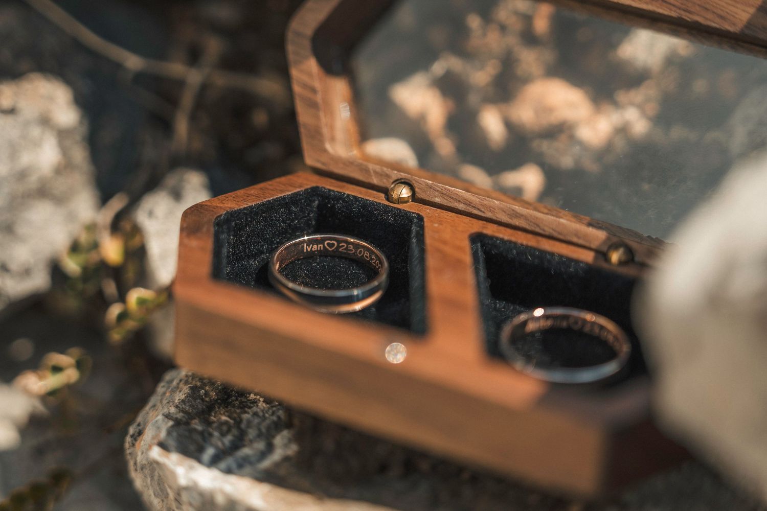 Elopement wedding rings holding in hands full of sand