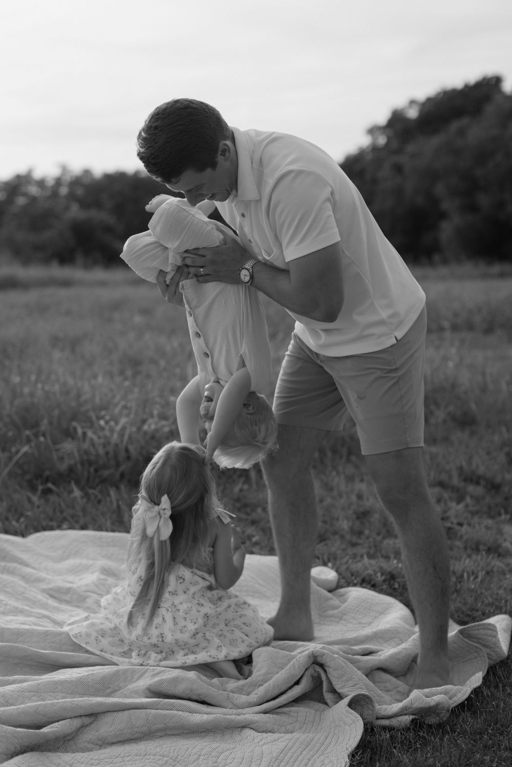 Person kneeling on white fabric spread out on grass, working with their hands in a focused manner.