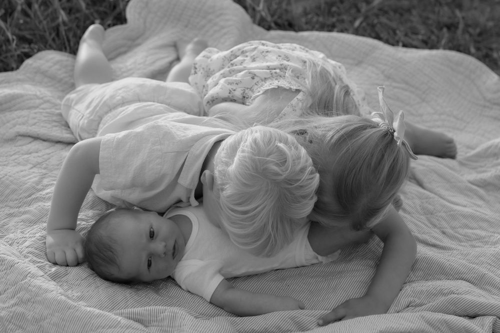 Black and white photograph of two children lying together on a blanket outdoors.