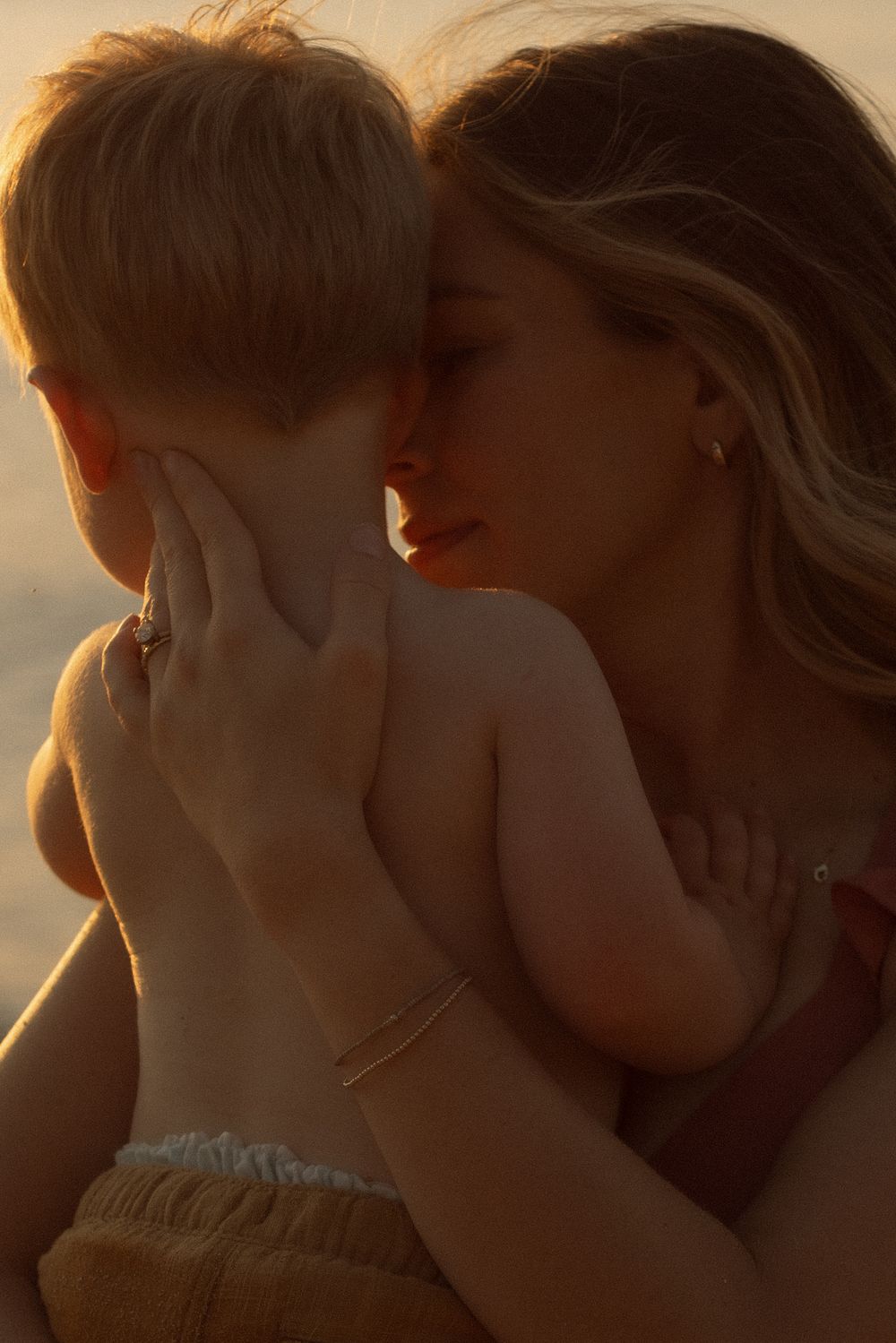 A tender moment between parent and child silhouetted against warm sunset lighting.