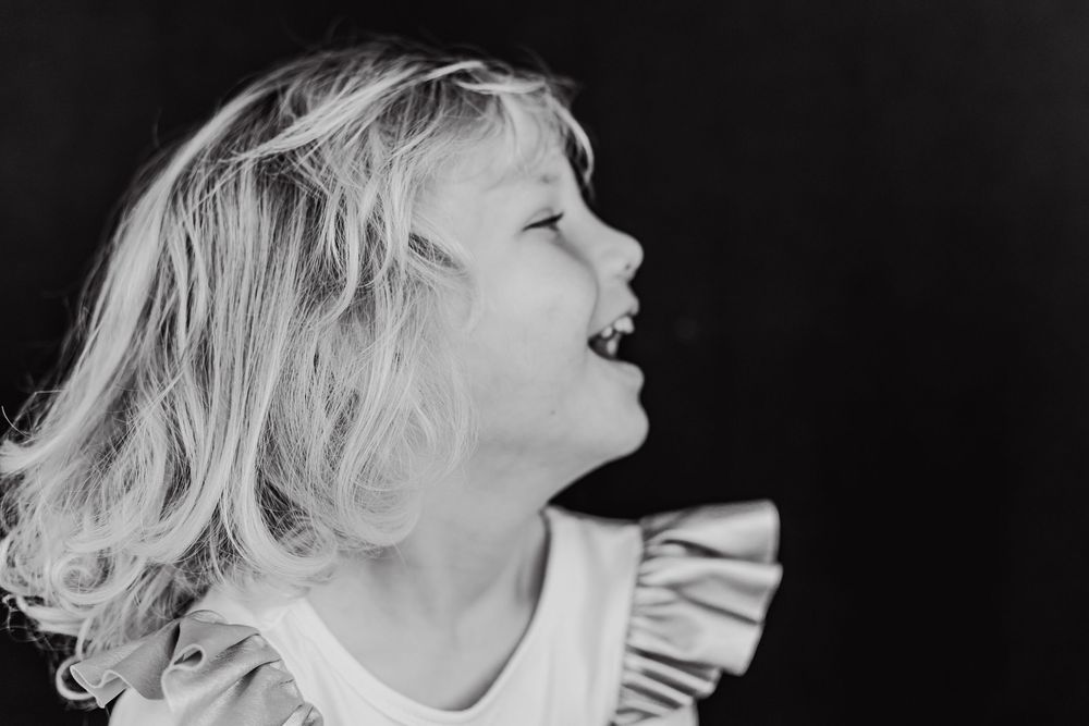 Profile black and white photo of school a young girl laughing and looking to the right.