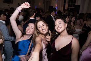 People dancing and celebrating at a lively party or nightclub event in a dimly lit venue.