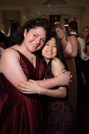Two people in formal attire share a joyful embrace on a dance floor.