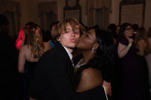 A couple shares an intimate moment while dancing together at a dimly lit formal event.