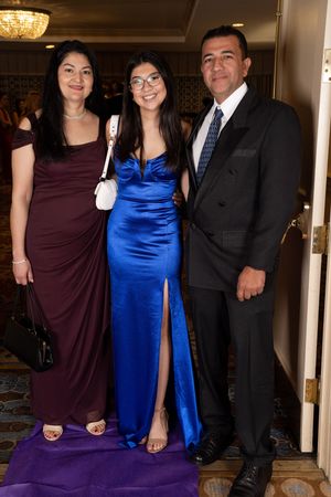 Formal gathering with evening attire including a royal blue gown, burgundy dress and black suit.