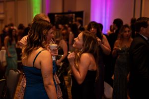 People dancing and socializing at an elegant evening event with purple mood lighting in the background.