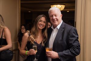 Guests enjoying drinks and conversation at an elegant evening event in a warmly lit venue.
