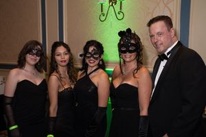A group of formally dressed guests at an elegant event with green accent lighting in the background.