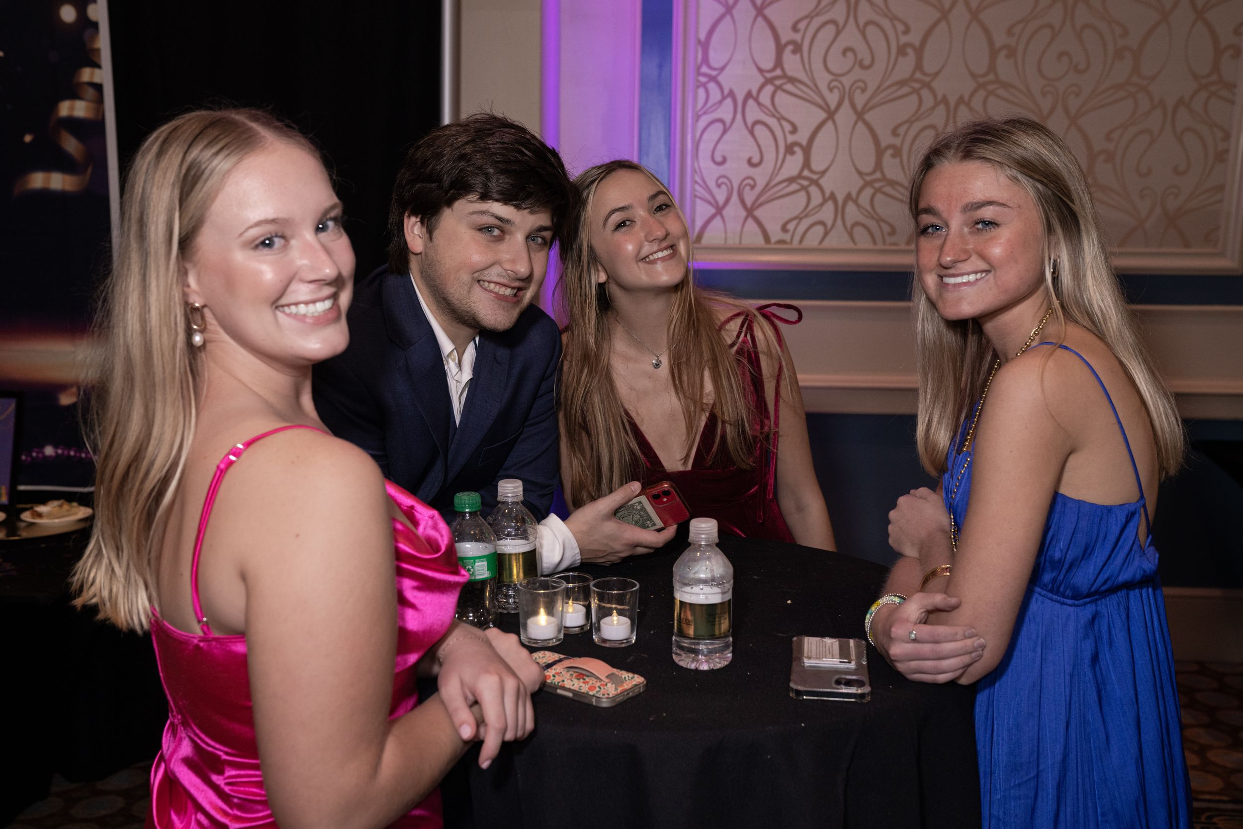 Group of party guests enjoying drinks and conversation at an elegant evening social gathering.