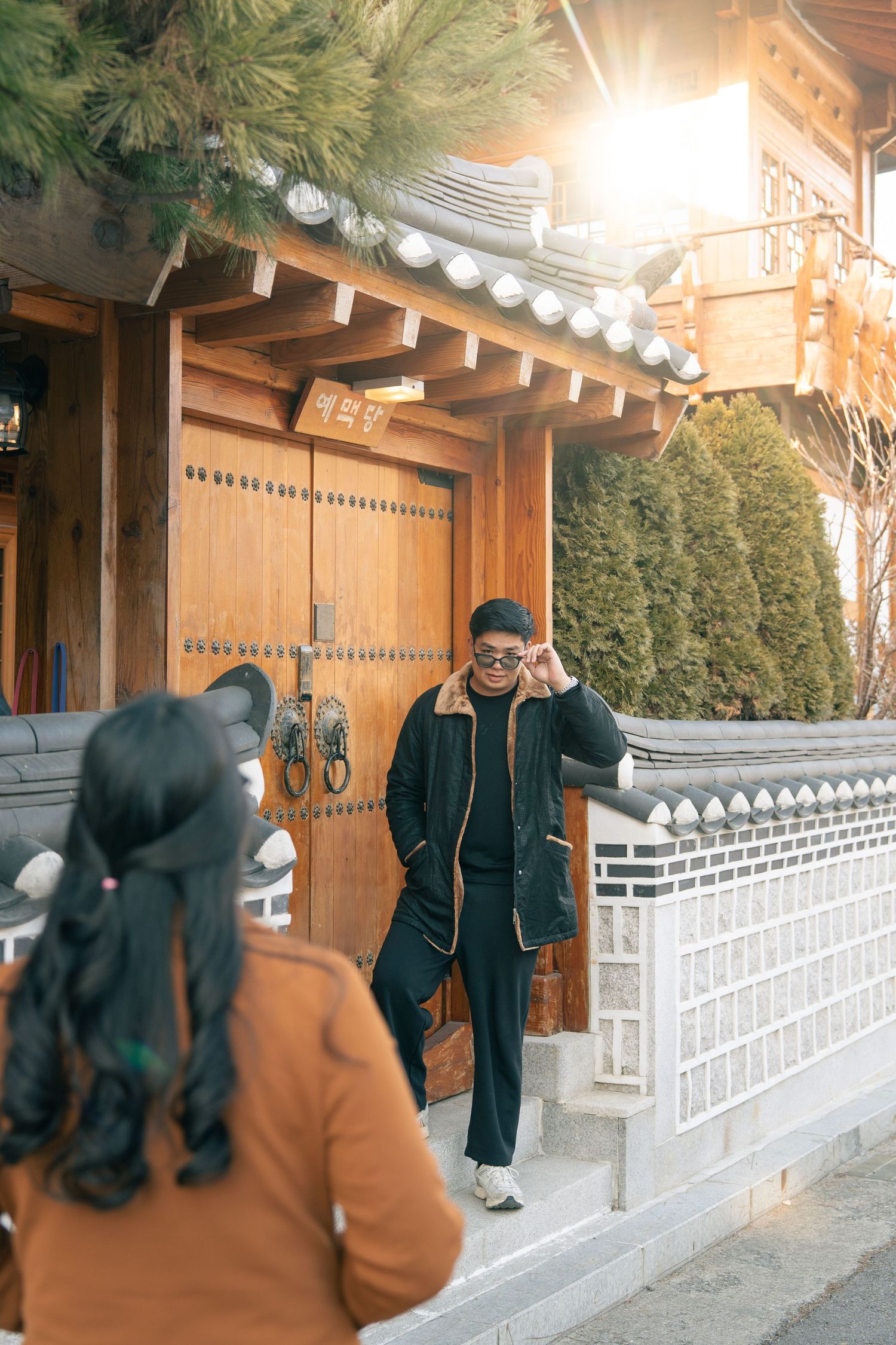 Traditional Korean hanok building with white stone walls and wooden beams illuminated by decorative string lights.