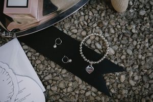 Wedding jewelry and accessories arranged on dark surface with scattered stones.