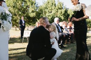 Wedding guests gather outdoors for celebration photos in natural lighting.