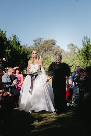 A wedding ceremony processional takes place in an outdoor garden setting.