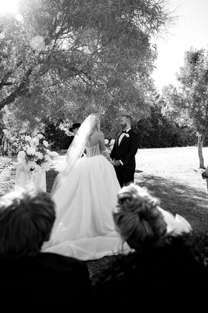 Black and white wedding ceremony photo captured through silhouetted guests.