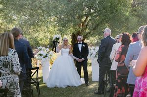 Outdoor wedding ceremony with guests gathered around in a garden setting.