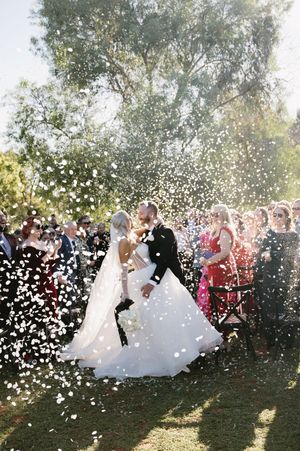 Wedding celebration moment captured with white confetti floating through the air during an outdoor ceremony.
