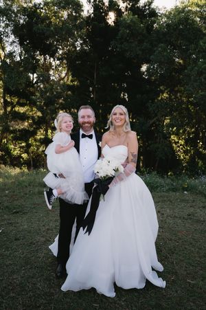 Wedding party poses together on a grassy hillside during golden hour celebrations.
