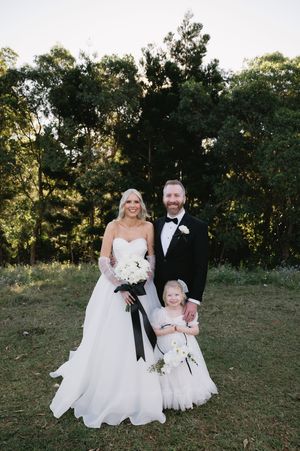 Wedding portrait taken outdoors with a scenic wooded background at sunset.