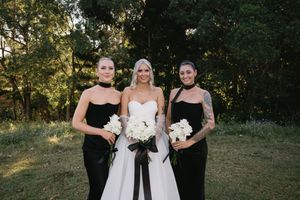 A group in formal black and white attire poses together in an outdoor garden setting during golden hour.