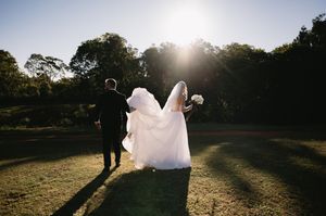 Silhouettes of wedding party members walking across a sunlit field during golden hour.