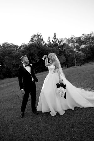 A series of black and white wedding photos showing a couple walking together on a grassy hillside in formal attire.