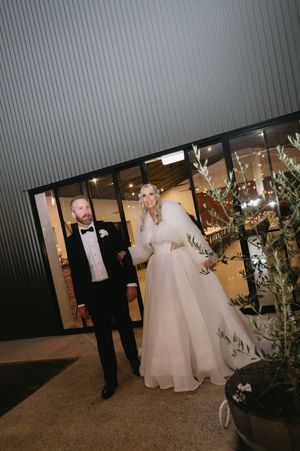 Wedding couple walking through an illuminated outdoor venue at night.