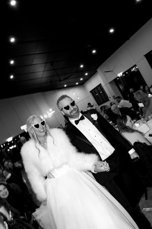 Wedding reception party with guests dancing in a dark venue with overhead lighting.