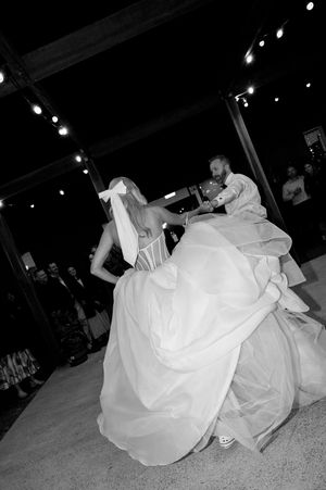 Black and white photos capture playful moments of a bride twirling in her flowing wedding dress on the dance floor.