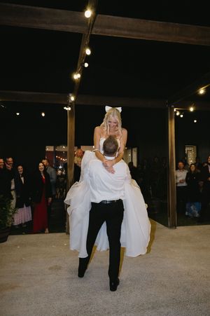 Wedding couple performs a dramatic dip dance move under outdoor string lights.
