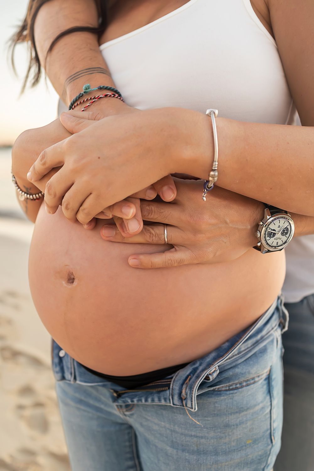 Close-up shots of a pregnant belly in blue jeans showing progression of a growing baby bump.