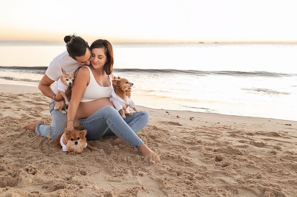 Couple sharing romantic moments together on a sandy beach during sunset.
