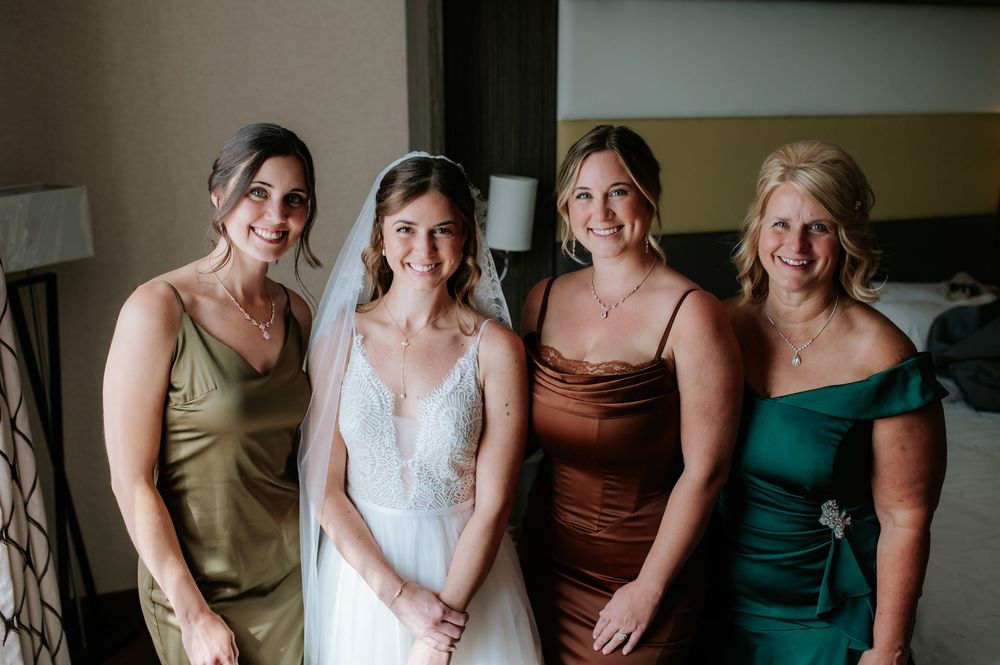 A bridal party poses together wearing elegant dresses in earth tones and jewel colors.