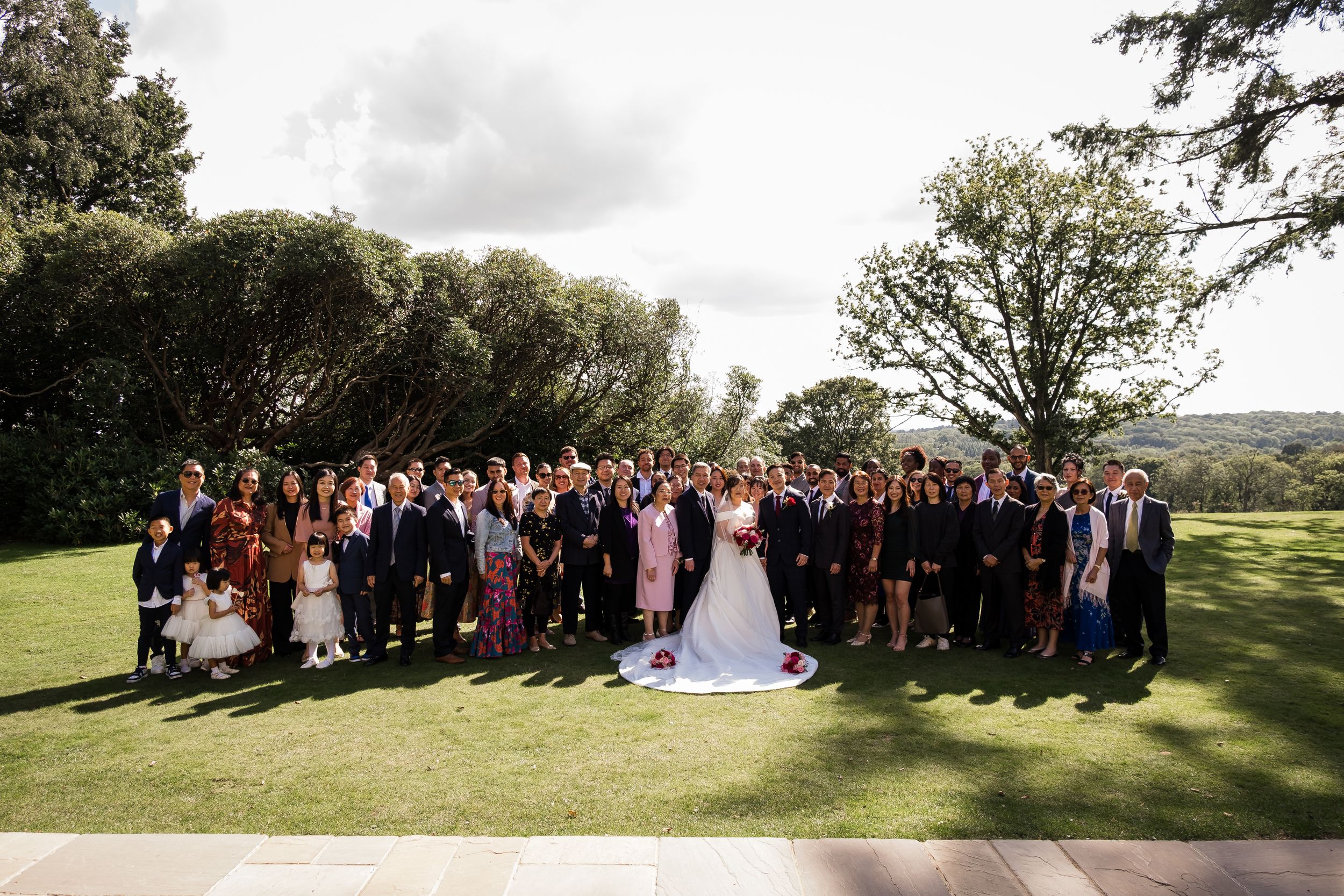 Wedding party group photos taken outdoors in a scenic countryside setting with rolling hills and trees in the background.